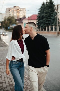 Young couple kissing demonstrating love on urban sidewalk