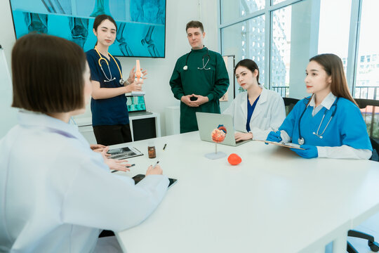 Group of diverse medical doctors and specialists discussing anatomical models during clinical seminar