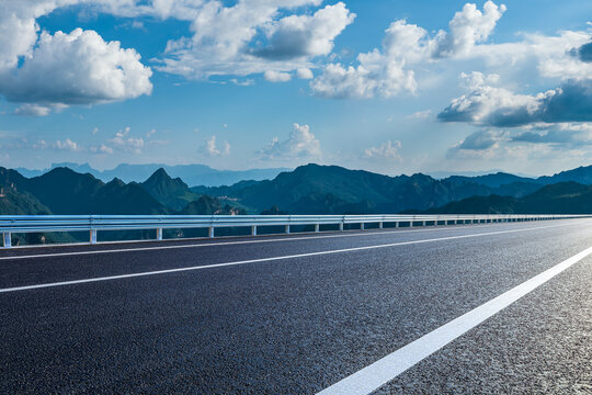 Asphalt highway running through a majestic mountain landscape under a clear blue sky