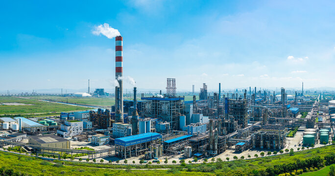 Aerial view of a modern petrochemical refinery with pipelines and smokestacks under a blue sky in China