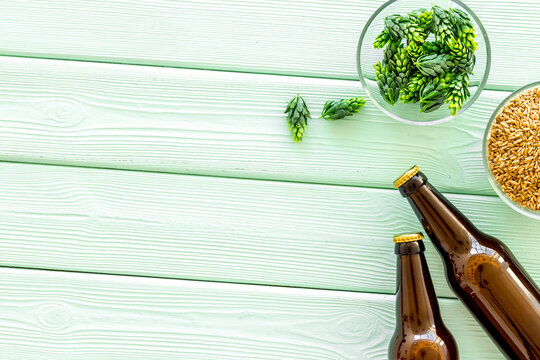 Barley and hop for making beer on green wooden background top view copy space
