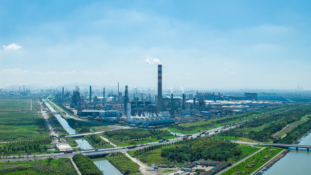 Aerial view of a modern petrochemical refinery with pipelines and smokestacks under a blue sky in China