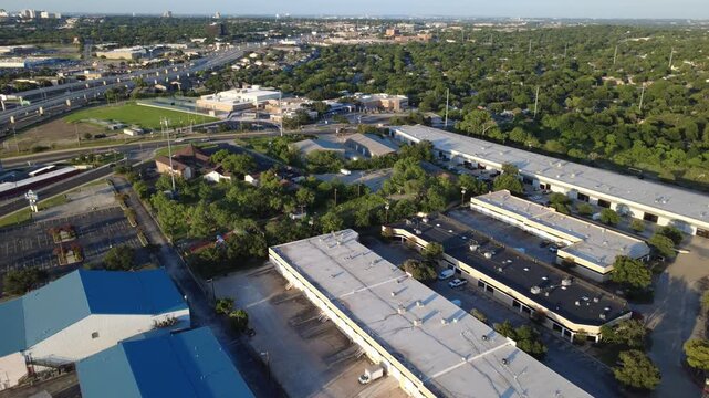 Expansive warehouse roofs span active commercial districts bordering Loop 410 in Bexar County. Industrial office parks meet dense residential greenbelt corridors, San Antonio, Texas