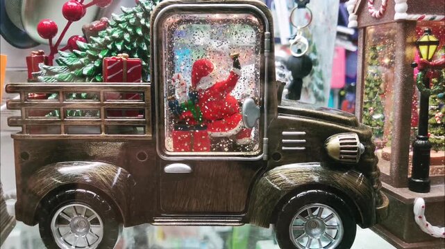 Vintage bronze truck snow globe with Santa Claus inside cabin, Christmas tree and gifts in the back. Festive holiday decoration with falling glitter for Christmas and New Year celebration concept.