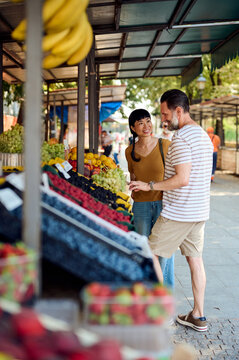 Happy Couple Shopping At Outdoor Farmers Market With Fresh Fruit And Casual Urban Lifestyle