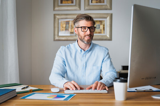 Confident middle-aged man using his computer at home and working