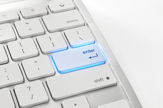 Close-up of a white computer keyboard with a glowing blue Enter key, representing technology, digital interaction, typing, commands and user interface
