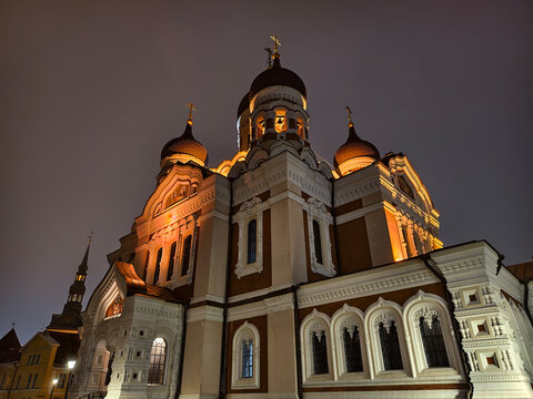 Low angle wide view of illuminated facade and onion domes of Alexander Nevsky Cathedral at night in Tallinn, Estonia
