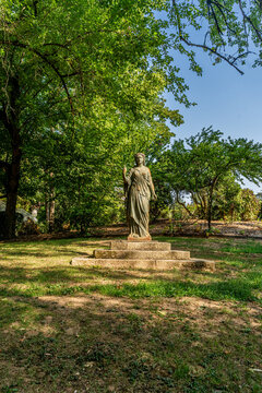 Classical Female Statue on Stone Pedestal in Green Public Park Garden