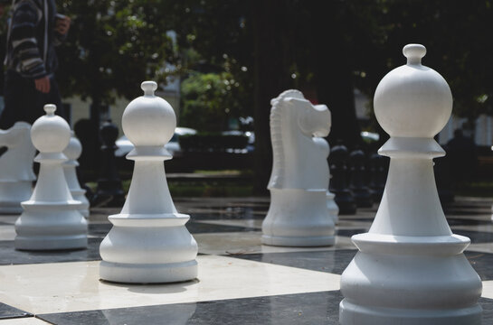 Big outdoor chess pieces on a public chessboard in a park