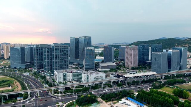 A panoramic view of a modern urban business district with high-rise buildings, elevated roads and green landscapes.