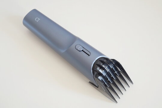 Modern cordless Xiaomi hair trimmer featuring an extended transparent comb guard attachment and slider switch, isolated on a light background. 