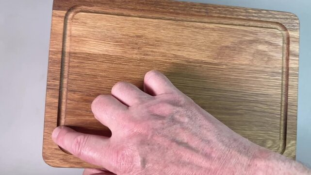 Oak cutting board with groove in hands on gray background