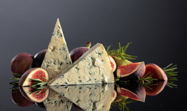 Blue cheese with fresh figs and rosemary on a black background.