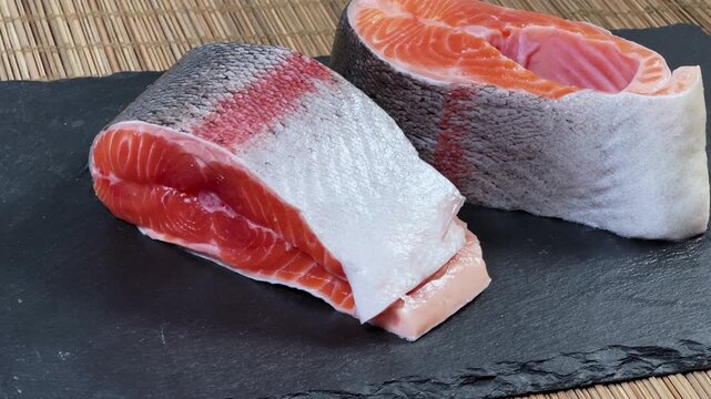 Pieces of raw rainbow trout on flat black slate plate