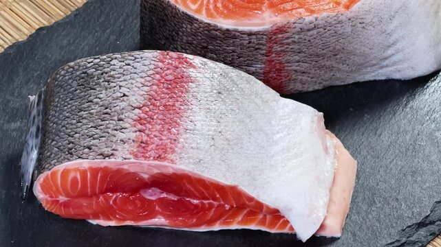 Pieces of raw rainbow trout on flat black slate plate