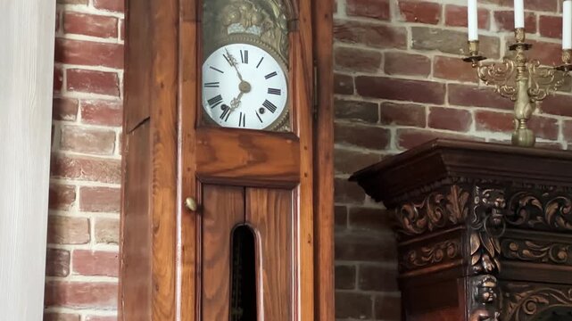 Antique longcase floor clock in wooden case against brick wall