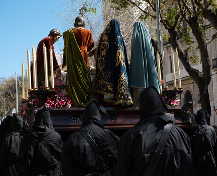 A Holy Week procession in Spain featuring a local religious brotherhood with hooded penitents and a float bearing religious images, which has been designated a site of international tourist interest.