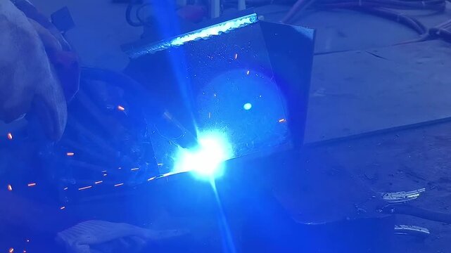 Arc welding operation on thick metal workpiece with flying sparks and bright blue welding arc video with sound
