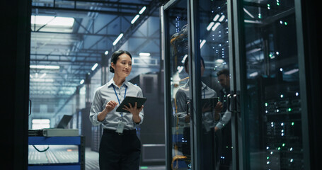 Fototapeta premium Asian Female Data Engineer Using Digital Tablet Computer Beside Server Cabinet, Performing Firmware Audit and Cable Management Review in High Performance Machine Learning Supercomputer Facility.