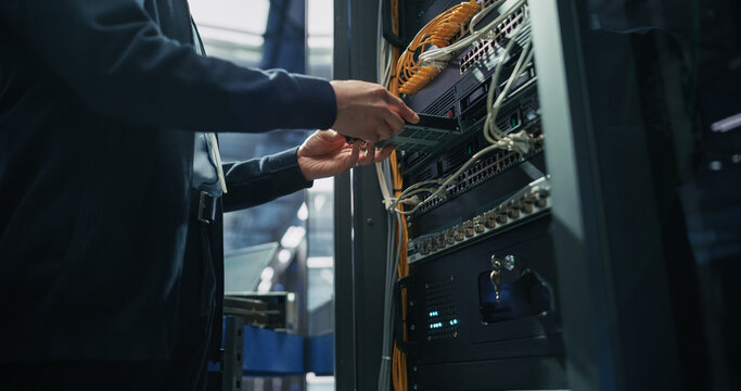 Close up of Technician Hands Installing Blade Server Hardware Module Into Rack Cabinet, Replacing Network Switch Component and Connecting Ethernet Cables in Artificial Intelligence Data Center.
