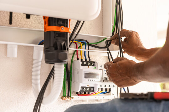 Closeup of technician installing solar photovoltaic hybrid inverter into a residential house