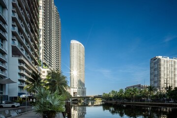 Fototapeta premium Miami river skyline with sunburst reflection between residential towers