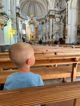 Curious Child Sitting on Wooden Bench in Cathedral