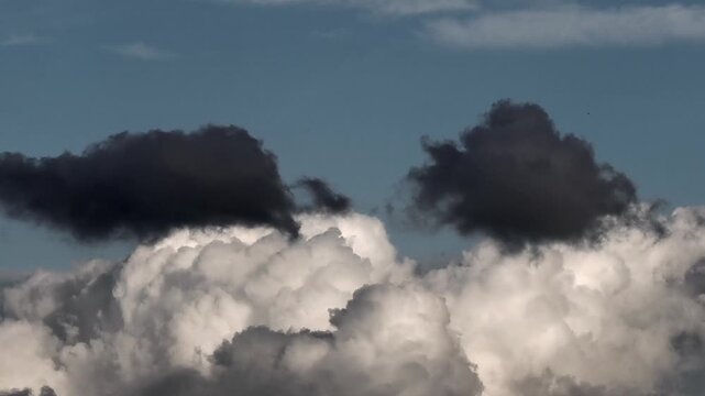Dynamic clouds featuring bright white cumulus bases overlaid with darker cloud fragments ranging from slate gray to near-black.