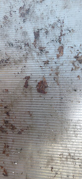 Dirty corrugated plastic sheet surface with dried leaves