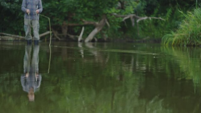 Young adult fisherman fly fishing on the small shallow river and casts