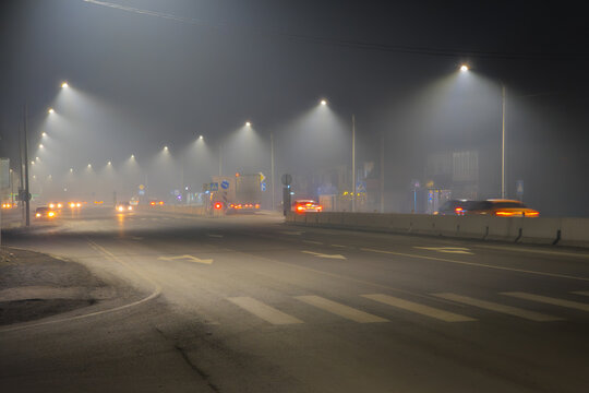 Foggy Night Street Scene with Traffic and Streetlights