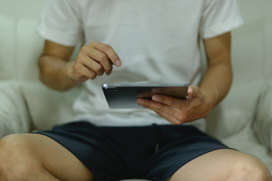 Person Sitting on Couch Using Tablet Device with Casual Clothing and Relaxed Posture