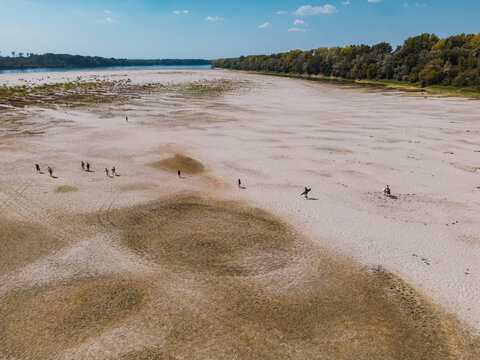 Aerial view of people walking across exposed sandy sandbars on Danube River, highlighting extreme drought and low water levels caused by climate change. APATIN, SERBIA - AUGUST 4, 2026