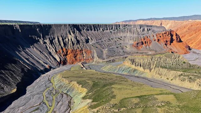 Aerial view of the colorful canyon with red and grey geological cliffs and a winding road on the slope in Anjihai Grand Canyon, Xinjiang, China