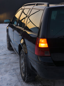 Black Station Wagon Parked on Snowy Ground at Sunset