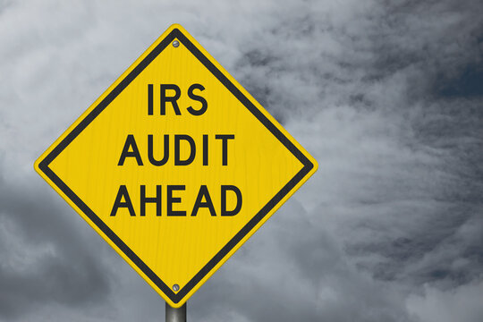IRS Audit Ahead yellow warning sign with stormy sky tax review