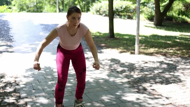 Young woman learns to skate backward in a sunny park struggling to keep balance as awkward moves and funny mistakes turn rollerblading practice into a playful challengeup