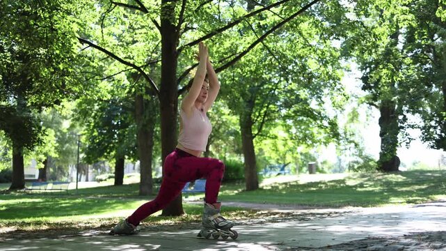 Woman humorously combines yoga with roller skating in a sunny park holding a lunge pose on inline skates and turning an ordinary workout into a playful balance challenge