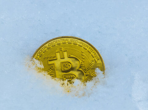 Golden Bitcoin Coin Partially Submerged in Snow