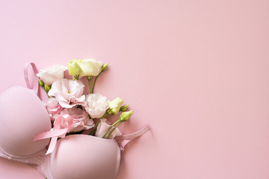 Pink bra and ribbon with delicate flowers on soft pink background for Breast Cancer Awareness month campaign and hope