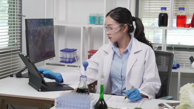An Asian female food scientist wearing safety glasses and gloves holds fresh broccoli and carrots, inspecting their quality for pesticide residues or chemical contaminants in a food research laborator