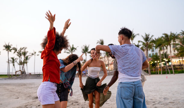 Diverse and multicultural friends dancing on the beach during a summer trip, celebrating friendship