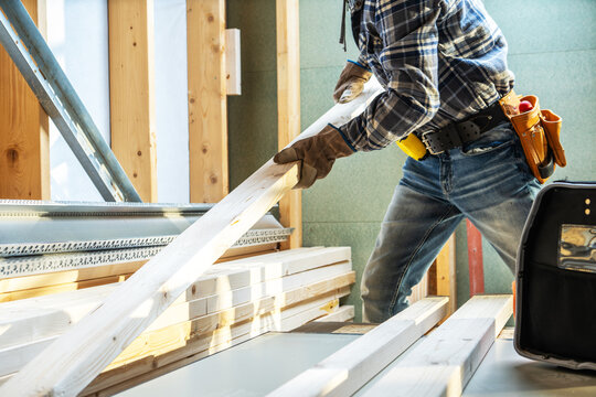 Worker carries wooden boards in construction site during day