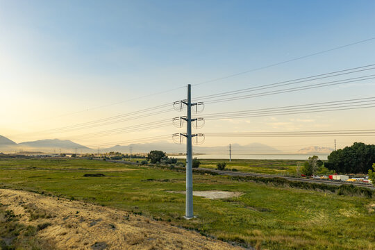 American Fork, Utah, United States - 10 August 2026: Aerial view of high power electrical transmission lines at sunrise along the Utah Lake shoreline with golden light.