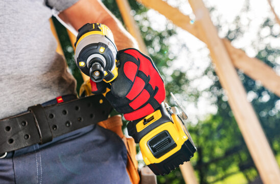Worker holds a tool at a construction site during daylight