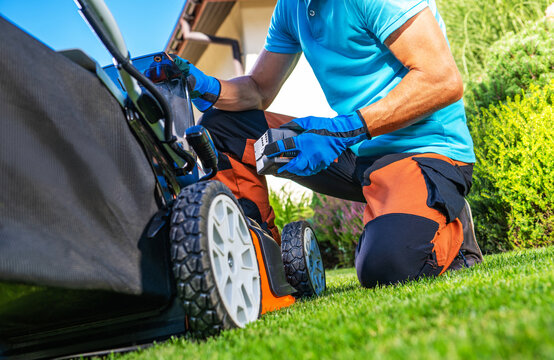 Person working on lawn mower in the garden during sunny day