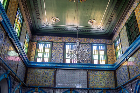 Chandelir hanging from a wooden ceiling, surrounded by painted tiles, in the El Ghriba Synagogue in Erriadh, Djerba, Tunisia