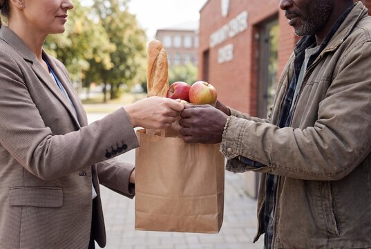 Volunteer handing food bag with groceries to poor man charity concept