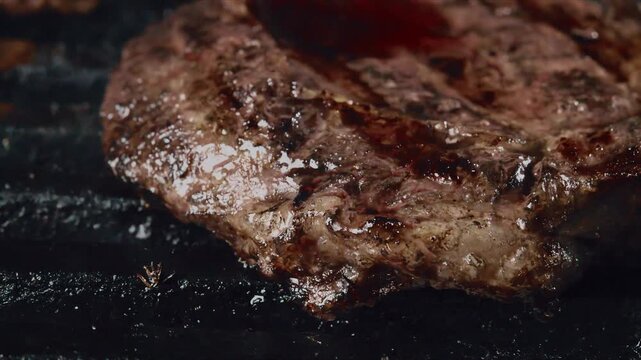 Close up of a juicy marbled steak sizzling on a hot grill with rich brown sear marks